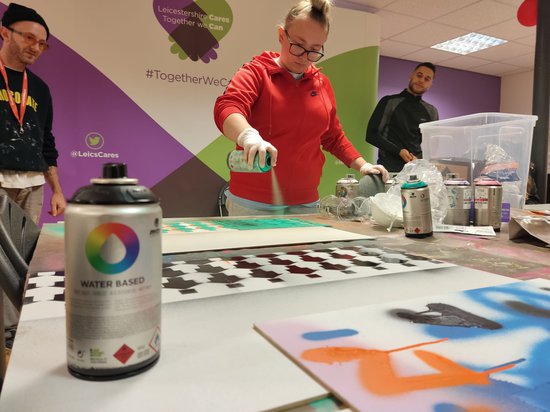 A group of young people in a room creating spray paint art